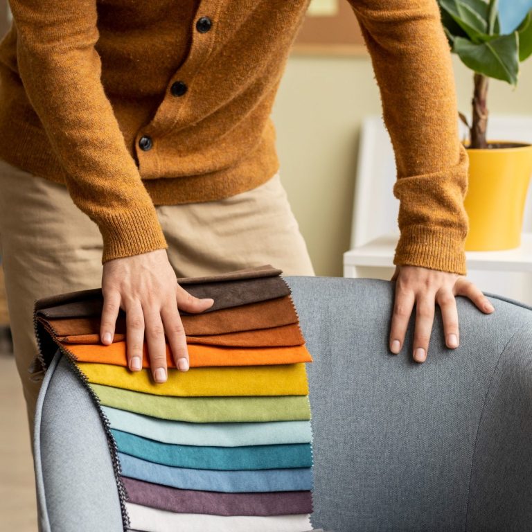 Person qui retapisse un fauteuil avec un tissu multicolore d'un dossier.
