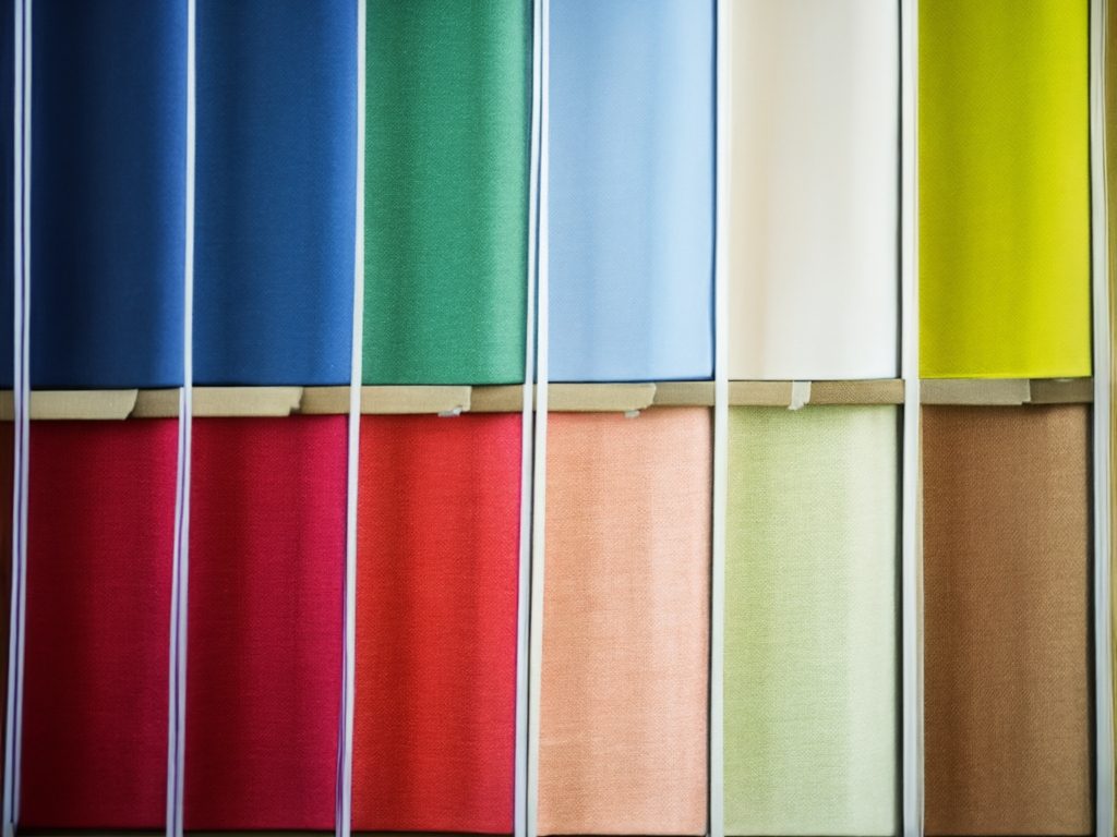 Tissus colorés sur des rouleaux, avec une palette allant des tons vifs aux pastels.