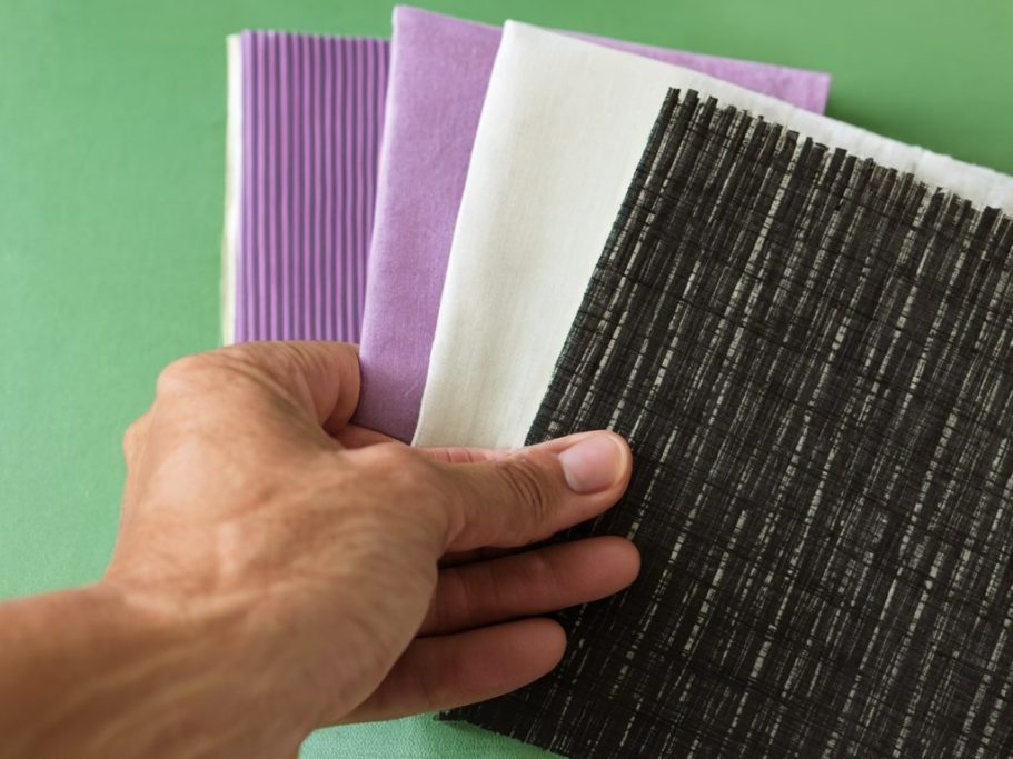 Main dans un assortiment de échantillon colorés : violet, blanc et noir.